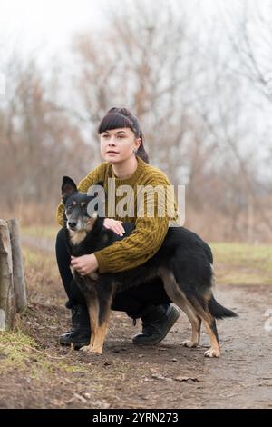Frau, die ihren Hund im Herbst in einem Park in der Nähe des Flusses begleitet Stockfoto