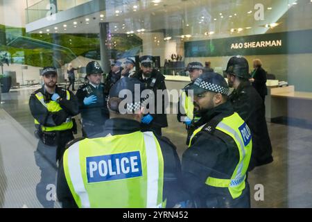 London, Großbritannien. Dezember 2024. Aktivisten des Klimawandels von Extinction Rebellion und Anwälte sind verantwortlich, die Büros der Londoner Anwaltskanzlei A&O Shearman wegen ihrer Arbeit mit Öl- und Gaskunden ins Visier zu nehmen und sie dazu aufzufordern, die Beziehungen zu Unternehmen mit fossilen Brennstoffen zu beenden. Mehrere Aktivisten wurden verhaftet, nachdem die Lobby besetzt war, ein Demonstrant saß auf einem Stativ und das Gebäude wurde mit gefälschtem Öl besprüht. Quelle: Eleventh Photography/Alamy Live News Stockfoto