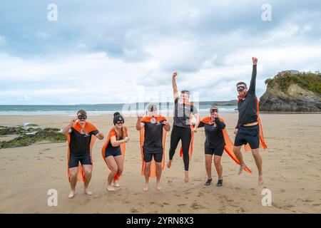 Die Teilnehmer treffen sich am Strand von Towan und bereiten sich auf die jährliche Veranstaltung „Superhero in the Cold“ vor, um Spenden für die britische Krebsforschung zu sammeln. Stockfoto