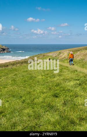 Eine Frau, die ihre Hunde entlang des South West Coast Path in der Nähe des abgeschiedenen Polly Porth Witzes an der Küste von Newquay in Cornwall in Großbritannien führt. Stockfoto