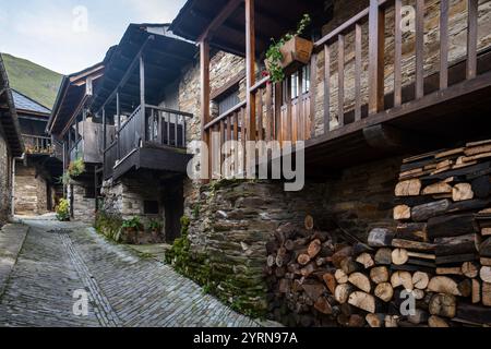 Steinhäuser mit Holzbalkonen, die eine enge Kopfsteinpflasterstraße in einem Bergdorf säumen Stockfoto