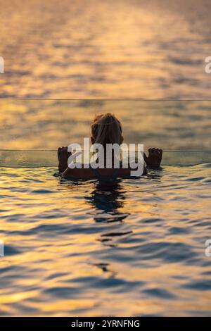 Silhouette einer Frau, die sich am Rand des Infinity-Pools auf dem Achterdeck des Expeditionskreuzfahrtschiffs SH Diana (Swan Hellenic) bei Sonnenuntergang bei s entspannt Stockfoto