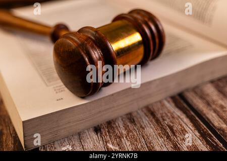 Der Holzhammer ruht auf einem offenen Gesetzbuch und symbolisiert Gerechtigkeit, Legalität und die Macht des Hofes. Stockfoto