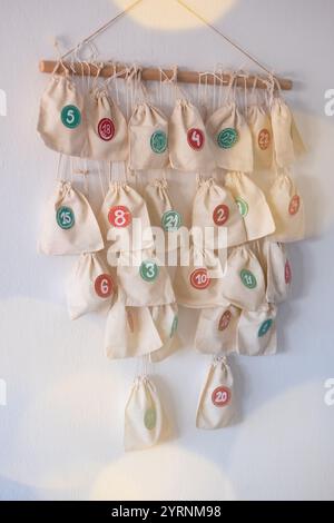 DIY Adventskalender mit Stofftüten, die an einer Holzstange hängen und mit den Zahlen 1 bis 24 an den Taschen hängen. Stockfoto