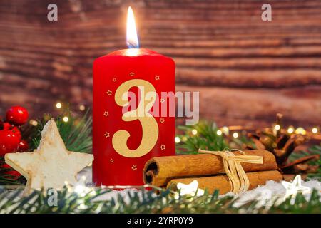 4. Dezember 2024: Die dritte Adventskerze brennt für die dritte Adventskerze. Eine rote Kerze mit der Nummer 3 vor der Weihnachtsdekoration. FOTOMONTAGE *** Dritte Adventskerze zum dritten Adventbrennt. Eine rote Kerze mit der Zahl 3 vor weihnachtlicher Dekoration. FOTOMONTAGE Stockfoto