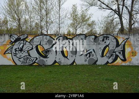 Die Zeichnung, Graffiti mit dem Wort GOLV, ist auf einem weißen, grauen Betonzaun gemalt. Grauer Hai mit Mütze und grauen Buchstaben, schwarzen Linien. Stockfoto