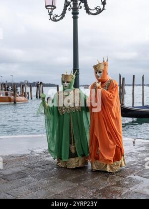 Paare in wunderschönen Karnevalskostümen auf den Straßen von Venedig, Italien, am Canal Grande während des Karnevals von Venedig. Stockfoto