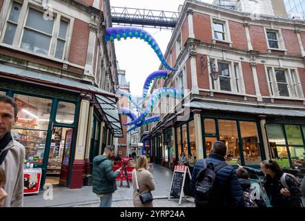 Leadenhall Market Leadenhall Market ist ein überdachter Markt in der City of London, der seit 1972 als Grade-II*-Bauwerk unter Denkmalschutz steht. Bereits im 14. Jahrhundert trafen sich rund um das Leadenhall Herrenhaus Geflügel- und Käsehändler. 1463 bekam er das Waagenrecht für Wolle, 1488 das Monopol für den Handel mit Leder. Durch den großen Brand von London 1666 wurden auch große Teile des Marktes zerstört. Das anschließend errichtete langjährige Provisorium wurde 1881 von Sir Horace Jones umgebaut, der auch den Billingsgate Market und den Smithfield Market entworfen hat. Eine Überdachu Stockfoto