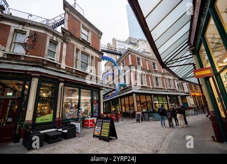 Leadenhall Market Leadenhall Market ist ein überdachter Markt in der City of London, der seit 1972 als Grade-II*-Bauwerk unter Denkmalschutz steht. Bereits im 14. Jahrhundert trafen sich rund um das Leadenhall Herrenhaus Geflügel- und Käsehändler. 1463 bekam er das Waagenrecht für Wolle, 1488 das Monopol für den Handel mit Leder. Durch den großen Brand von London 1666 wurden auch große Teile des Marktes zerstört. Das anschließend errichtete langjährige Provisorium wurde 1881 von Sir Horace Jones umgebaut, der auch den Billingsgate Market und den Smithfield Market entworfen hat. Eine Überdachu Stockfoto