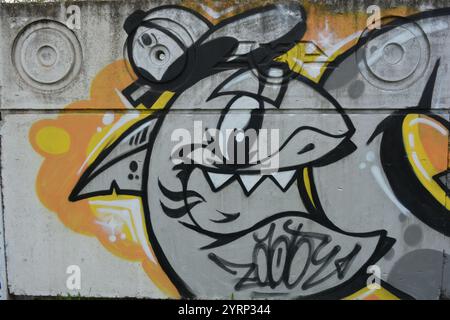 Die Zeichnung, Graffiti mit dem Wort GOLV, ist auf einem weißen, grauen Betonzaun gemalt. Grauer Hai mit Mütze und grauen Buchstaben, schwarzen Linien. Stockfoto