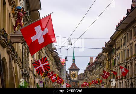 Wunderschöne alte Hauptstraße mit altem Gebäude und Flaggen an einem regnerischen Tag in Bern, Kanton Bern, Schweiz. Stockfoto