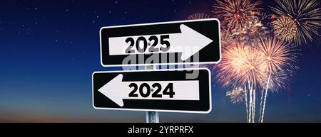 Straßenschilder zeigen den Weg zum neuen Jahr 2025 und zum alten Jahr 2024 am Nachthimmel mit Feuerwerk, kreativer Idee. Wählen Sie einen neuen Weg in das Jahr 2025, Co Stockfoto