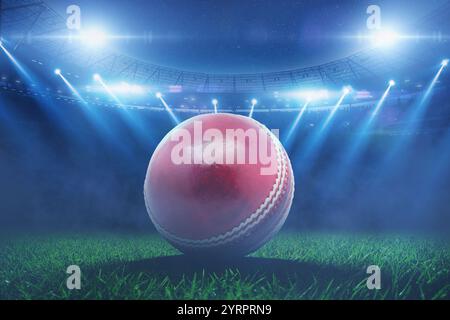 Der rote Cricketball aus Leder liegt im Stadion mit blauen Flutlichtern während des Cricketturniers auf dem Gras. Cricket Championship, kreative Idee Stockfoto