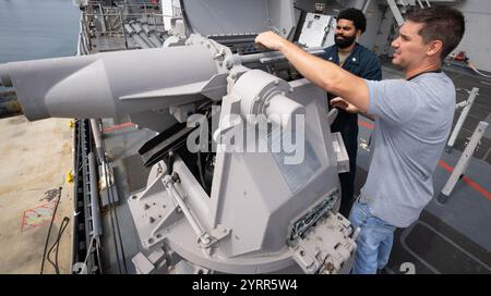 USS Comstock (LSD 45) Gunner’s Mate 1st Class Petty Officer Isiah Johnson (links) und James Holle, MK 38 in-Service Engineering Agent beim Naval Surface Warfare Center (NSWC) Indian Head Division in Picatinny Detachment in New Jersey, installieren am 3. Juni 2024 die Feeder-Baugruppe eines der MK 38 Maschinengewehre an Bord der LSD 45 während eines Schiffspflegs in der NSWC Port Hueneme Division in Kalifornien. Die Zuführungseinheit wird regelmäßig zu Inspektions- und Wartungszwecken entfernt, um die Betriebsbereitschaft zu gewährleisten. (US Navy Foto von Eric Parsons/veröffentlicht) Stockfoto