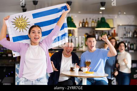 Fans mit der Flagge Uruguays feiern den Sieg ihrer Lieblingsmannschaft in der Bierstube Stockfoto