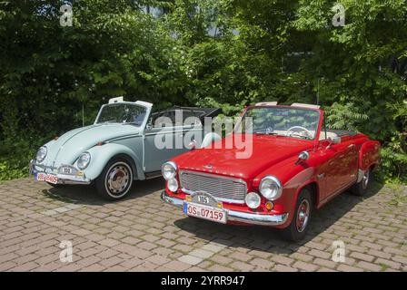 Zwei klassische Cabrios, eines rot und eines hellblau, nebeneinander auf einem gepflasterten Parkplatz geparkt, Oldtimer, Cabrio, VW, Volkswagen, Käfer Stockfoto