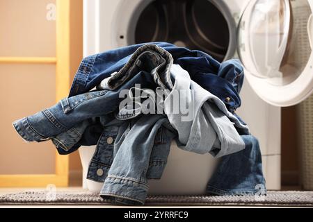 Waschmaschine mit schmutzigen Jeans und anderen Denim-Kleidern im Innenbereich Stockfoto