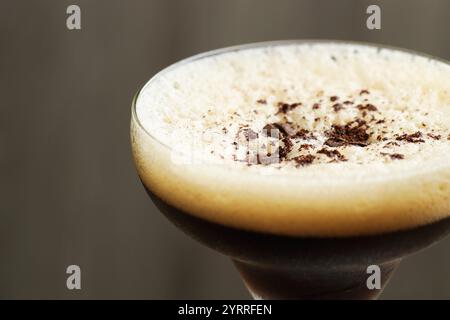 Köstlicher Espresso-Martini mit Kaffeebohnen im Glas auf verschwommenem Hintergrund, Nahaufnahme Stockfoto