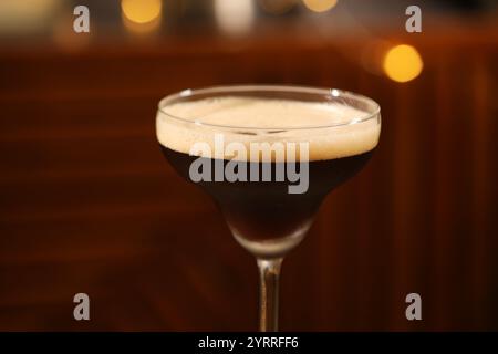 Köstlicher Espresso-Martini im Glas gegen verschwommenes Licht, Nahaufnahme Stockfoto