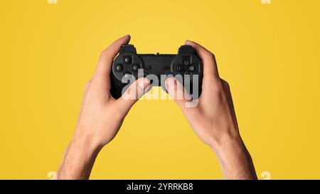Aktivitäten sperren. Millennial Mann hält Videospiel-Controller auf blauem Hintergrund, Nahaufnahme. Panorama Stockfoto