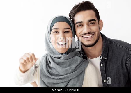 Emotionale junge Dame im Hijab, die den Schlüssel aus dem Haus zeigt Stockfoto