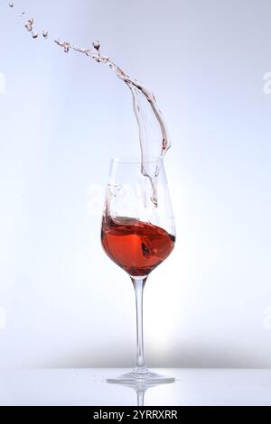 Rosenwein spritzt im Glas auf weißem Hintergrund Stockfoto