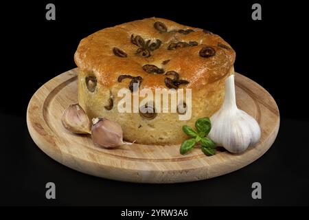 Rundes Focaccia-Brot mit Oliven, Knoblauch und Basilikumspalt auf schwarzem Hintergrund Stockfoto