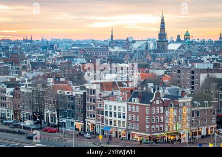 Gebäude der Skyline von Amsterdam während eines dramatischen goldenen Sonnenuntergangs. Foto am Abend in Amsterdam Niederlande Stockfoto