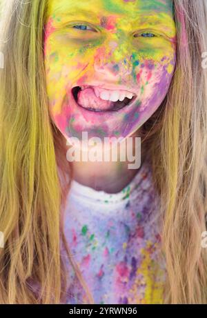 Sorgenfreier Zeitvertreib. Glückliches Leben in Teenagerzeit. Ferienlager. Emotionales Mädchen mit fröhlicher Stimmung mit bunten Farben. Farbenfrohe holi auf bemaltem Gesicht. C Stockfoto