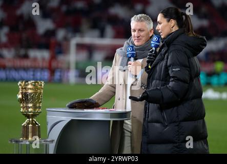 03. Dezember 2024, Bayern, München: Fußball: DFB-Cup, Bayern München - Bayer Leverkusen, Achtelfinale in der Allianz Arena. Ein Kameramann steht vor dem Spiel im Stadion. Bastian Schweinsteiger, TV-Experte und ehemaliger FC Bayern-Spieler und ARD-Moderatorin Esther Sedlaczek vor dem Spiel. Foto: Sven Hoppe/dpa - WICHTIGER HINWEIS: Gemäß den Vorschriften der DFL Deutschen Fußball-Liga und des DFB Deutschen Fußball-Bundes ist es verboten, im Stadion und/oder im Spiel aufgenommene Fotografien in Form von sequenziellen Bildern und/oder videoähnlichen Fotoserien zu verwenden oder zu verwenden. Stockfoto