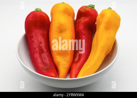 Leuchtende rote und gelbe Paprika in einer weißen Schüssel Stockfoto
