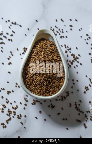 Brown Seeds elegant in einem Dekorationslöffel platziert, umgeben von verschütteten Seeds in der Nähe Stockfoto
