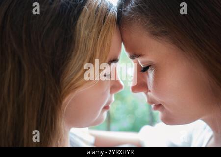 Tochter Mutter Bonding Indoor Foto: Zärtlicher Moment, der Liebe und Unterstützung zwischen einer Mutter und ihrer Tochter mit Down-Syndrom in Innenräumen festhält. Stockfoto