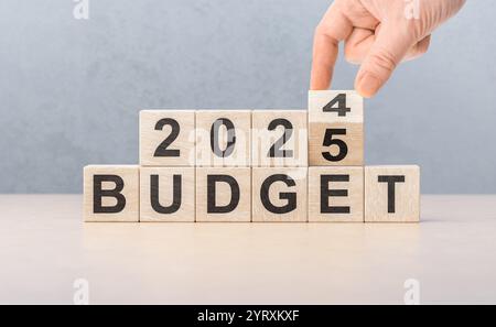 Geschäftskonzept der Planung 2025. Der Geschäftsmann kippt den Holzwürfel und ändert die Worte BUDGET 2024 in BUDGET 2025. Neujahr-Businessplan-Konzept 2025. Stockfoto