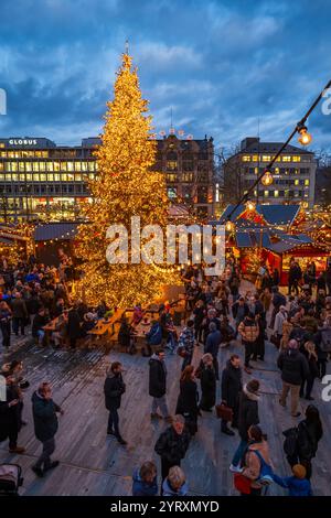 3-12-2024 Zürich, Schweiz. Besucher besuchen Pop-up-Shops auf dem Weihnachtsmarkt am Sechselautenplatz. Blaue Stunde am späten Abend, Weihnachtsbeleuchtung. Stockfoto