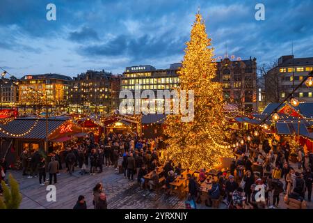 3-12-2024 Zürich, Schweiz. Besucher besuchen Pop-up-Shops auf dem Weihnachtsmarkt am Sechselautenplatz. Blaue Stunde am späten Abend, Weihnachtsbeleuchtung. Stockfoto