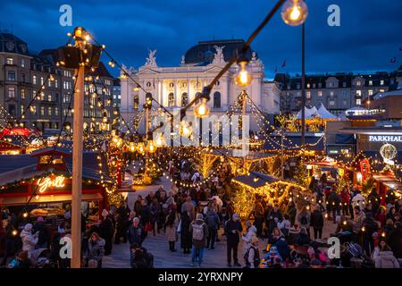 3-12-2024 Zürich, Schweiz. Besucher besuchen Pop-up-Shops auf dem Weihnachtsmarkt am Sechselautenplatz. Blaue Stunde am späten Abend, Weihnachtsbeleuchtung. Stockfoto