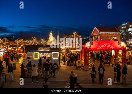 3-12-2024 Zürich, Schweiz. Besucher besuchen Pop-up-Shops auf dem Weihnachtsmarkt am Sechselautenplatz. Blaue Stunde am späten Abend, Weihnachtsbeleuchtung. Stockfoto