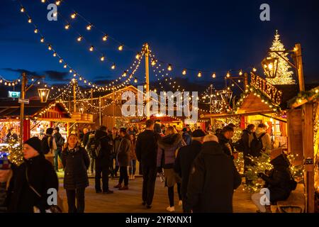 3-12-2024 Zürich, Schweiz. Besucher besuchen Pop-up-Shops auf dem Weihnachtsmarkt am Sechselautenplatz. Blaue Stunde am späten Abend, Weihnachtsbeleuchtung. Stockfoto