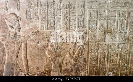 Die Abydos King List enthält die Namen von 76 Königen des alten Ägypten. Sie wurde an einer Wand des Tempels von Seti I. in Abydos, Ägypten, gefunden. Sie besteht aus drei Reihen mit 38 Kartuschen (Umrandungen, die den Namen eines Königs umschließen) in jeder Zeile. Die oberen beiden Reihen enthalten die Namen der Könige, während die dritte Reihe lediglich den Namen und das Nomen von Seti I. wiederholt. Das Relief zeigt Seti I. und seinen Sohn Ramesses II. Auf dem Weg zu einer Opfergabe an Ptah Seker Osiris im Namen ihrer 72 Vorfahren: Der Inhalt der Königsliste. Ramesses ist dargestellt, der Räuchergefäße hält. Stockfoto