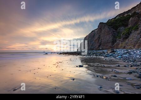 Die Küste von Dana Point spiegelt die warmen Farben des Sonnenuntergangs wider, während Klippen im Hintergrund aufragen und einen ruhigen Blick auf die Küste bieten. Stockfoto
