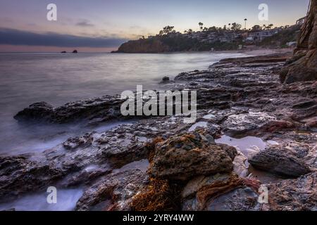 Die Wellen schlagen bei Sonnenuntergang sanft gegen die felsige Küste des Crescent Bay Beach und unterstreichen die ruhige Schönheit von Laguna Beach, Kalifornien. Stockfoto