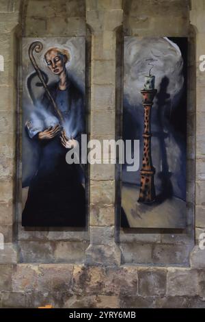 Romsey, Southampton, England. November 2024. Im Inneren der Romsey Abbey: Ein Diptychon von St. Ethelflaeda und ein hoher Kerzenleuchter des Künstlers Christopher Gollon. Stockfoto