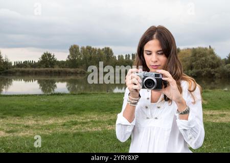 Touristen fotografieren die Natur mit analoger Kamera in einer friedlichen Landschaft mit See und Bäumen Stockfoto