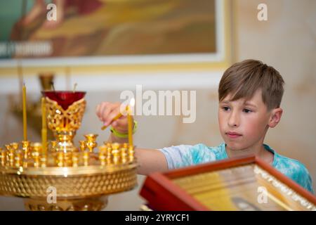 Ein Teenager stellt Kerzen in eine orthodoxe Kirche. Stockfoto