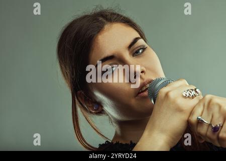 Junge Sängerin mit intensivem Blick, Mikrofon in der Hand und leidenschaftlich in einem Musikstudio, die ihre Liebe zu Musik und Kunst ausstrahlt Stockfoto