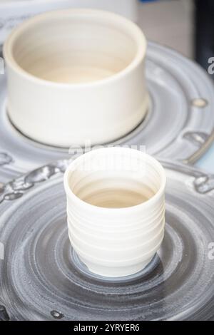 Die Hände Formen Ton auf einem Keramikrad, das traditionelle Handwerkskunst, Keramikkunst und handwerkliche Töpferei hervorhebt. Stockfoto