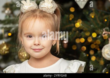 Nahaufnahme eines dreijährigen Mädchens vor einem Weihnachtsbaum. Stockfoto