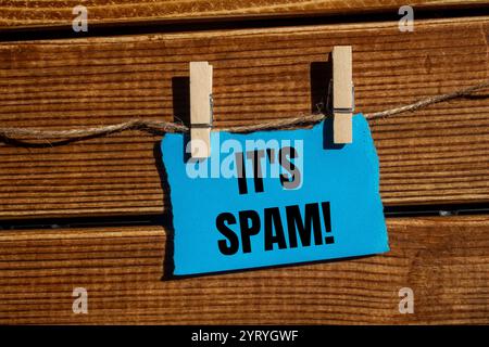 Es ist eine Spam-Nachricht, geschrieben auf zerrissenem blauem, zerrissenem Papierstück mit hölzernem Hintergrund. Konzeptionell ist das Spam-Symbol. Kopierbereich. Stockfoto