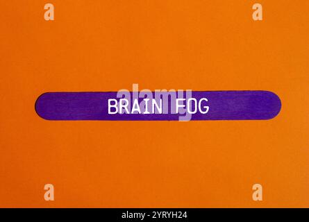Hirnnebel-Nachricht auf violettem Holzstab mit orangem Hintergrund. Konzeptionelles Hirnnebelsymbol. Kopierbereich. Stockfoto